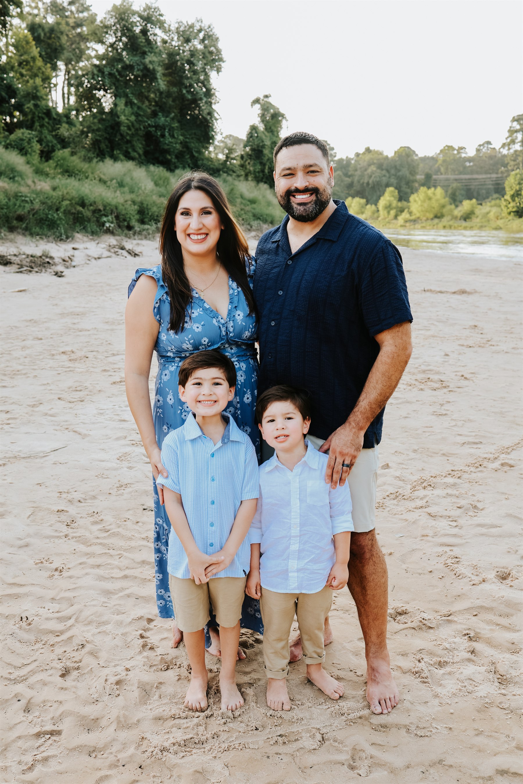 Jessica and her husband Derrick standing on a riverbank with their two young sons.