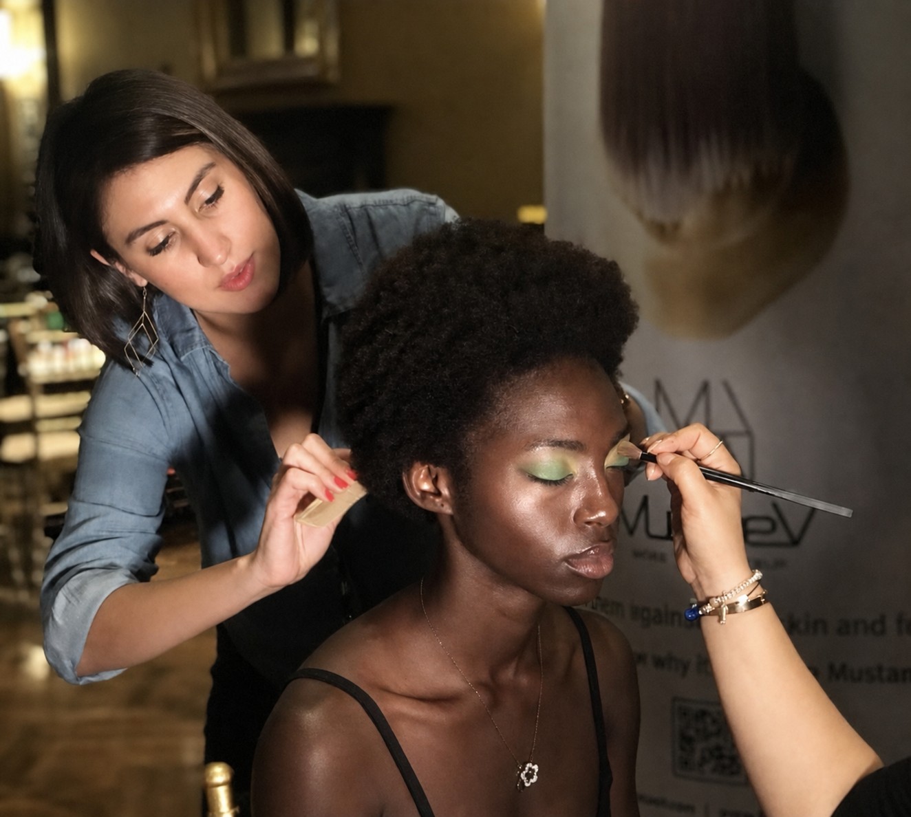 Jessica at work on a wedding morning, styling a client’s hair while another artist finishes her eye makeup.